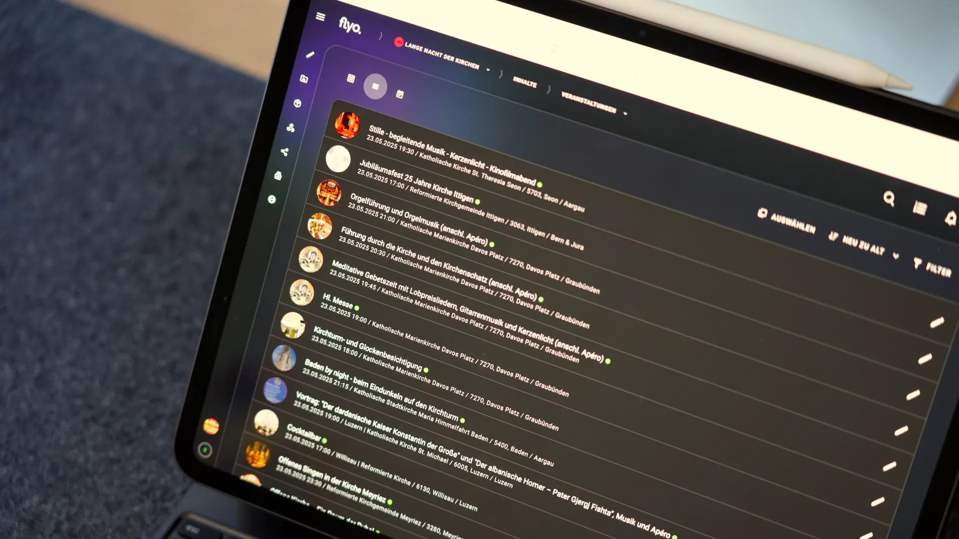 Tablet mit geöffnetem Chat-Interface: mehrere Nachrichtenzeilen mit Profilbildern, Eingabeleiste und Navigationsleiste, im Hintergrund ein Sofa.