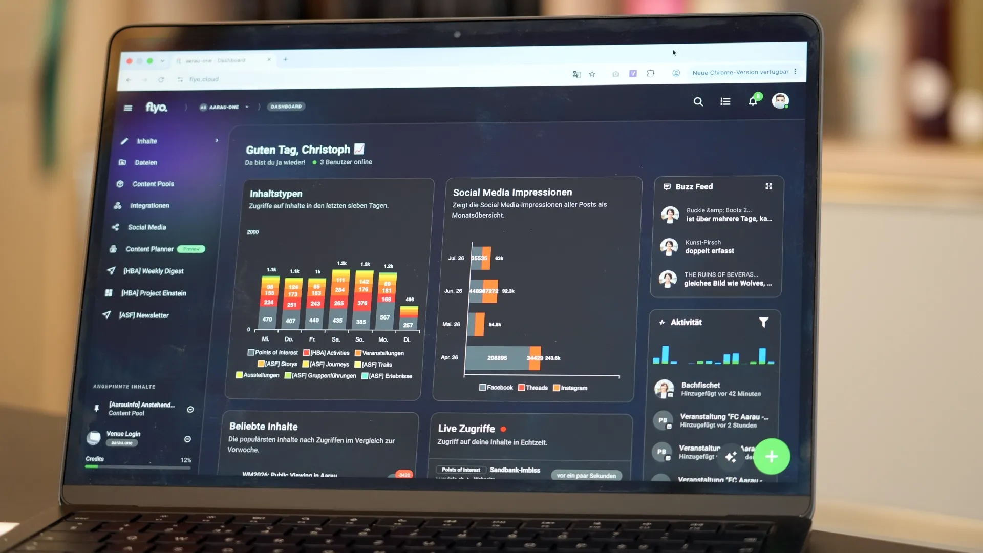 Laptop-Display mit Social-Media-Dashboard: Balken- und Diagrammanzeige, mehrere Module wie „Social Media Impressionen“, „Aktivität“ und „Live Zugriffe“.