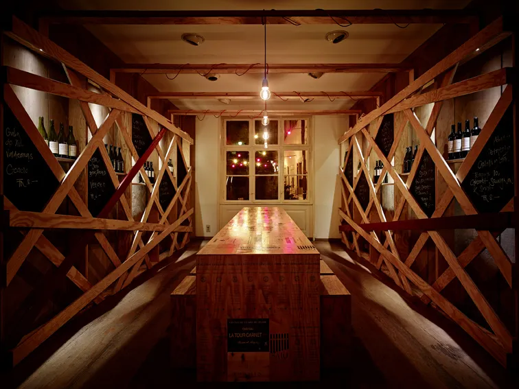 Innenbereich der invino Weinbar mit langem Holztisch in der Mitte, rechts und links Weine.