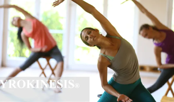 Drei Personen in einem Fitnessstudio trainieren mit Kettlebell-ähnlichen Positionen im Spiegel: eine Frau vorn im Unterarmstütz, beide anderen im Hintergrund im ähnlichen Bewegungsablauf.