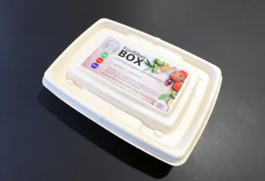 Fünf-Fiber-Box aus biologisch abbaubarem Material mit einem bunten Etikett, das Informationen zu Inhaltsstoffen und Lagerung enthält.