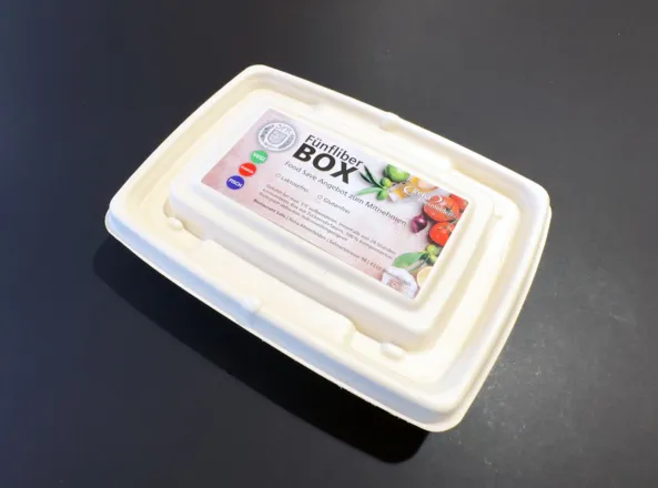 Fünf-Fiber-Box aus biologisch abbaubarem Material mit einem bunten Etikett, das Informationen zu Inhaltsstoffen und Lagerung enthält.