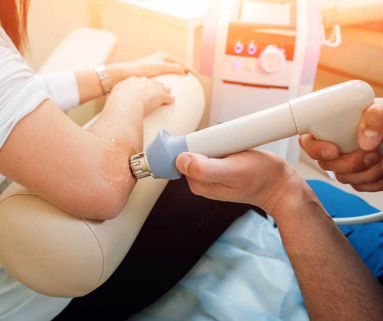 Medizinisches Ultraschallgerät untersucht den Ellenbogen einer sitzenden Person.