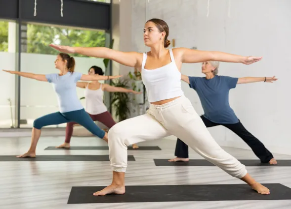 Women making yoga at gym. Virabhadrasana pose