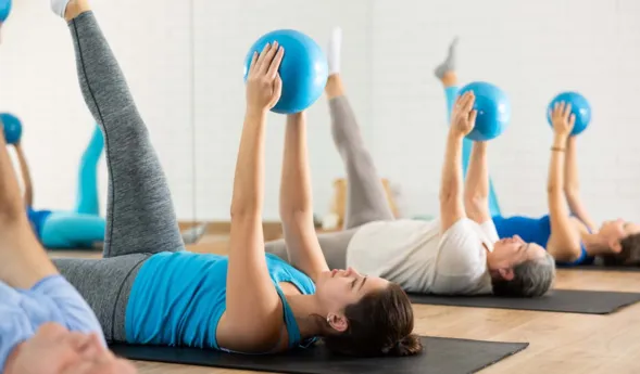 Portrait of young sporty girl during group core training with bender ball at gym. Healthy lifestyle and pilates concept