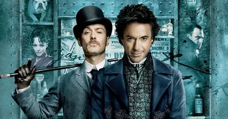 Zwei Männer in viktorianischer Kleidung stehen vor einer Wand mit Zeitungsartikeln. Der Mann links trägt einen Zylinder und hält einen Stock, während der Mann rechts einen eleganten Mantel mit einem auffälligen Muster trägt. Beide blicken direkt in die...