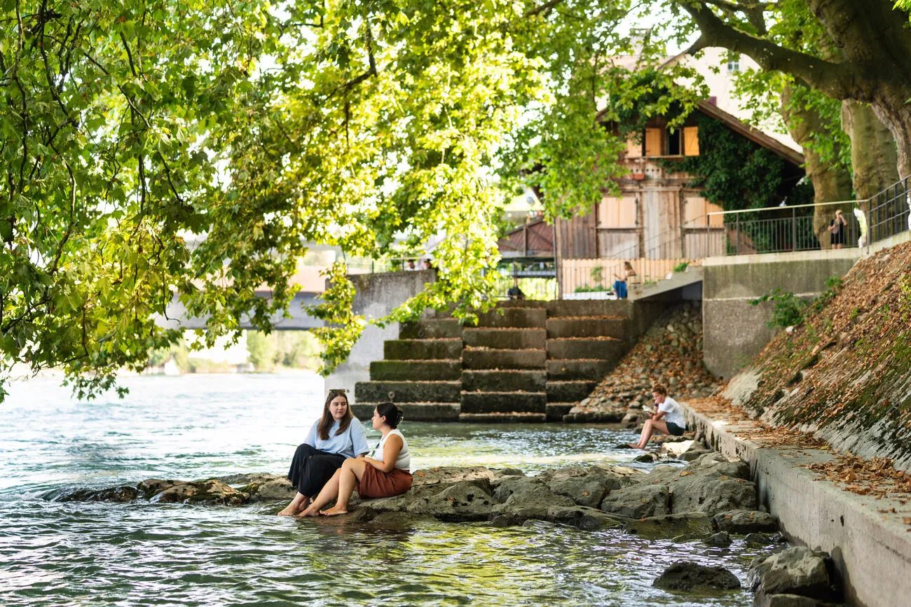 Personen entspannen an der Limmat.
