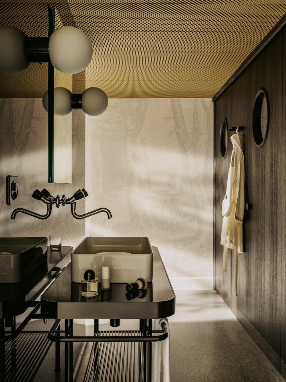 Detailverliebter Waschbereich: Das Lavabo hat eine Insel, in die Toilette und die Dusche blickt  man durch ein rundes Fenster. Kosmetikprodukte von  Soeder stehen zur Benutzung bereit.