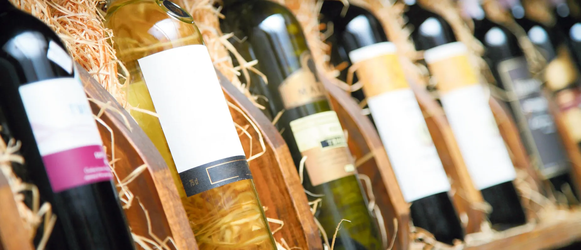 Closeup shot of wineshelf. Bottles lay over straw.